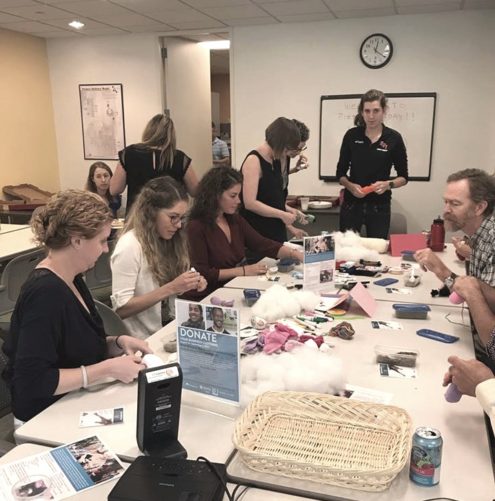 people around a table making cat toys