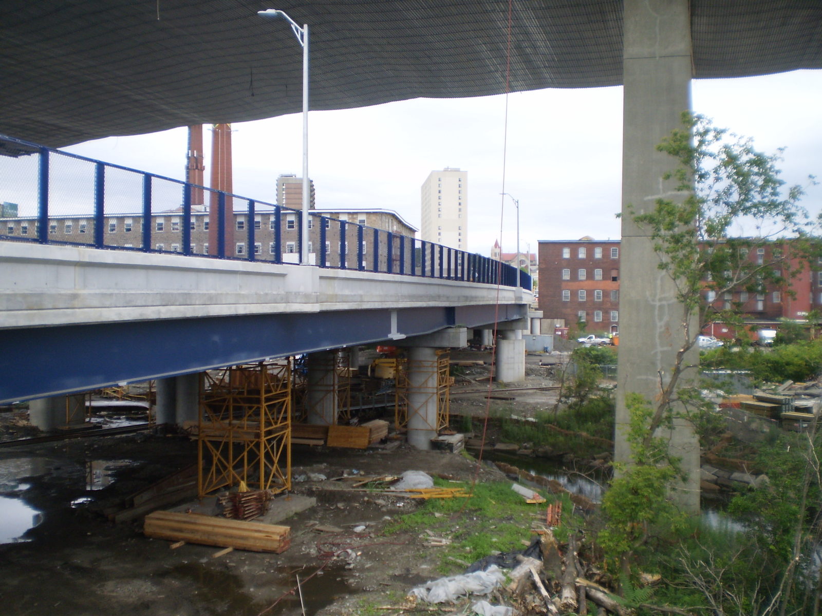 small blue fenced bridge under highway bridge