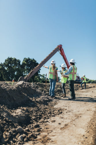 GEI employees in hardhats and yellow vests on construction site