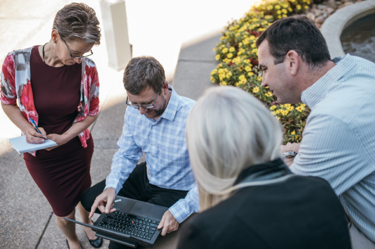 people gathering around man with laptop