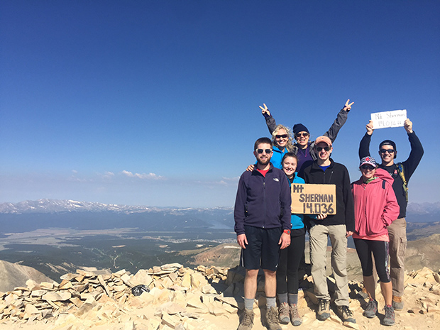 people holding up signs at the top of a mountain