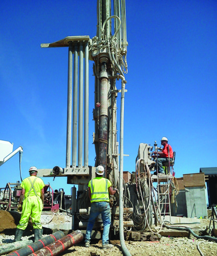 construction workers in yellow vest with a drill rig