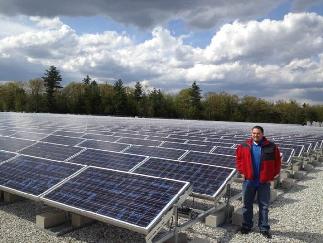 GEI employee by solar panels