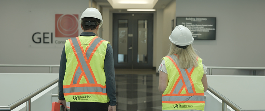 Man and woman with hard hats walking into office