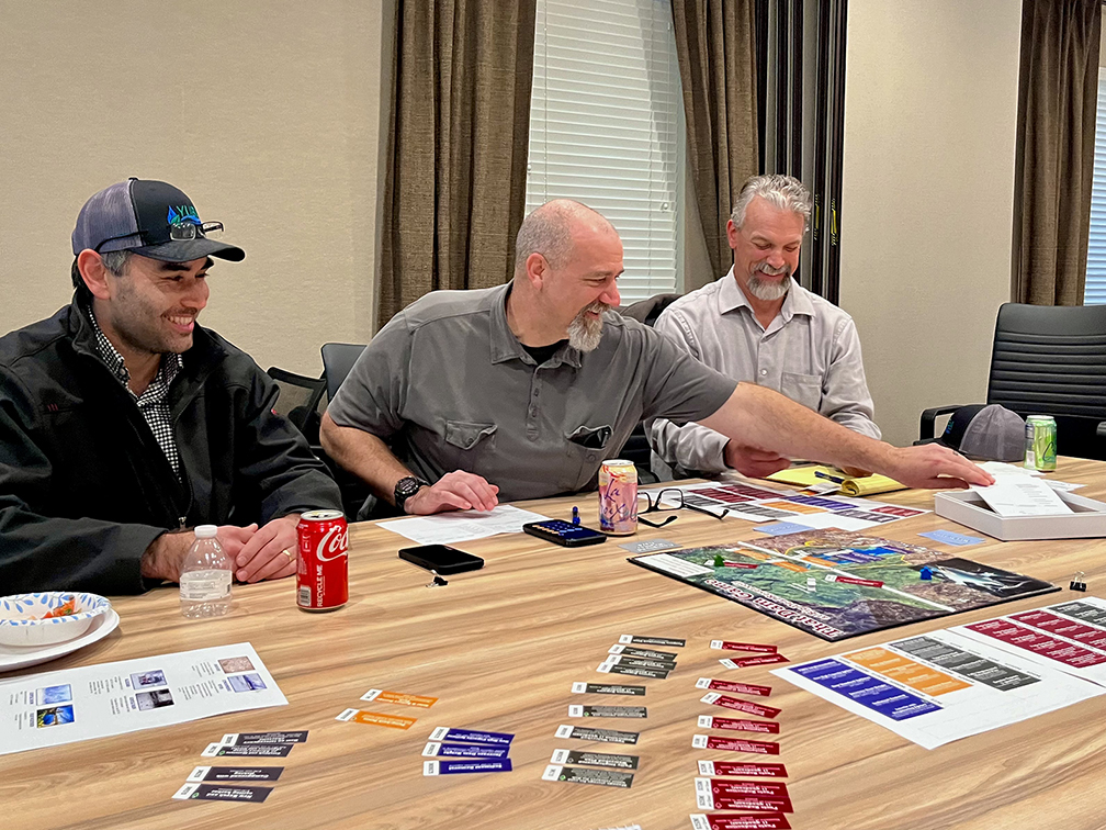 Men in chairs at table playing a board game