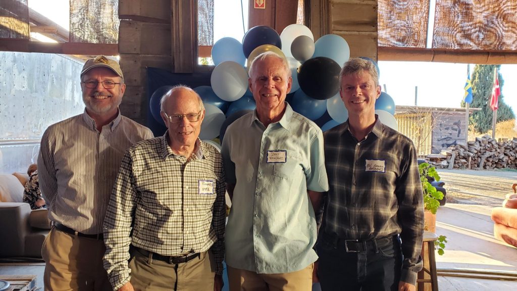 Four men posing in front of balloons