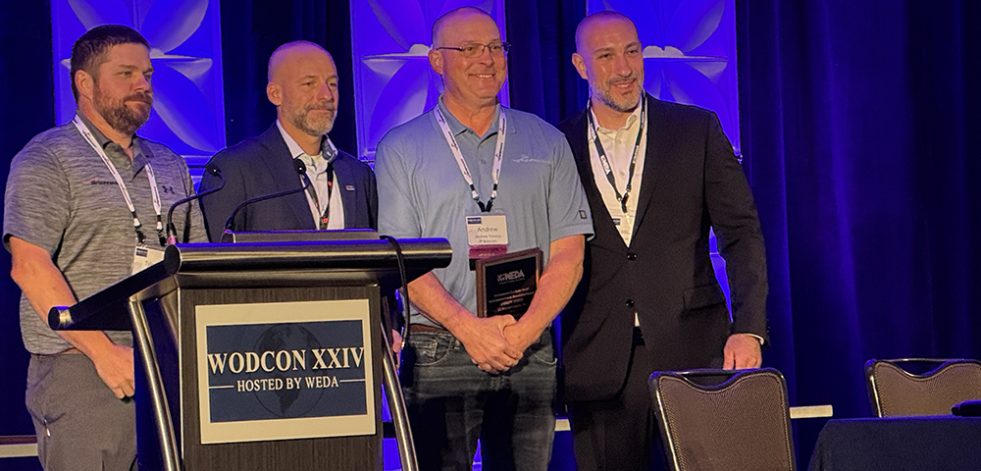 Men behind podium holding award