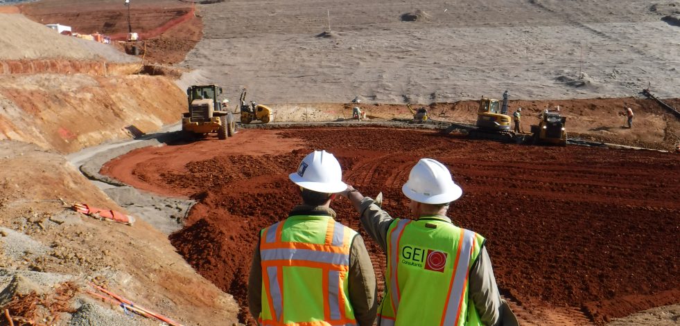 Men in construction helmets and safety vest standing in front of the El Dorado Forebay Dam construction.