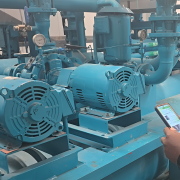 Hands holding mobile phone in front of industrial machinery