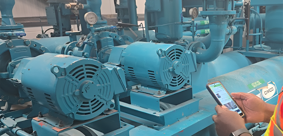 Hands holding mobile phone in front of industrial machinery