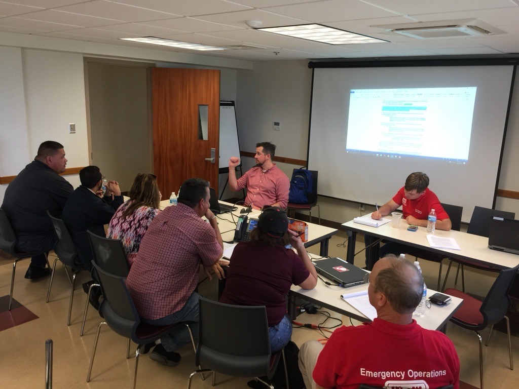Man teaching in classroom with men and women at tables listening